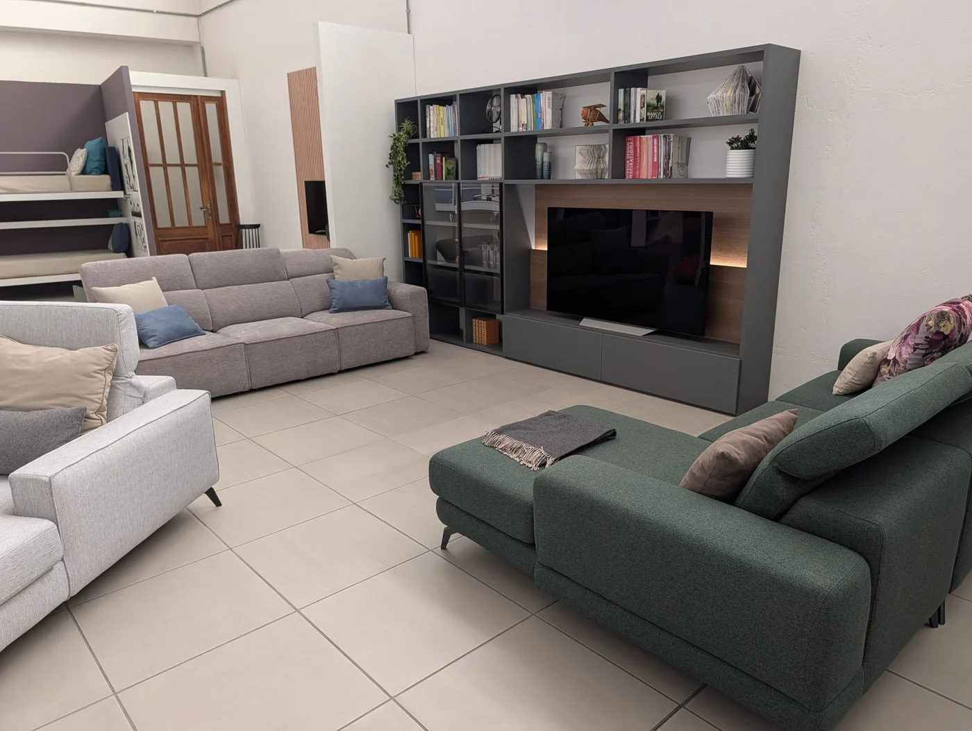 Divani e parete attrezzata con libreria nella zona soggiorno dello showroom di Veduggio
